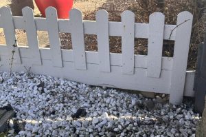 A Simple action to help hedgehogs: a small gap under a garden fence forming a hedgehog highway